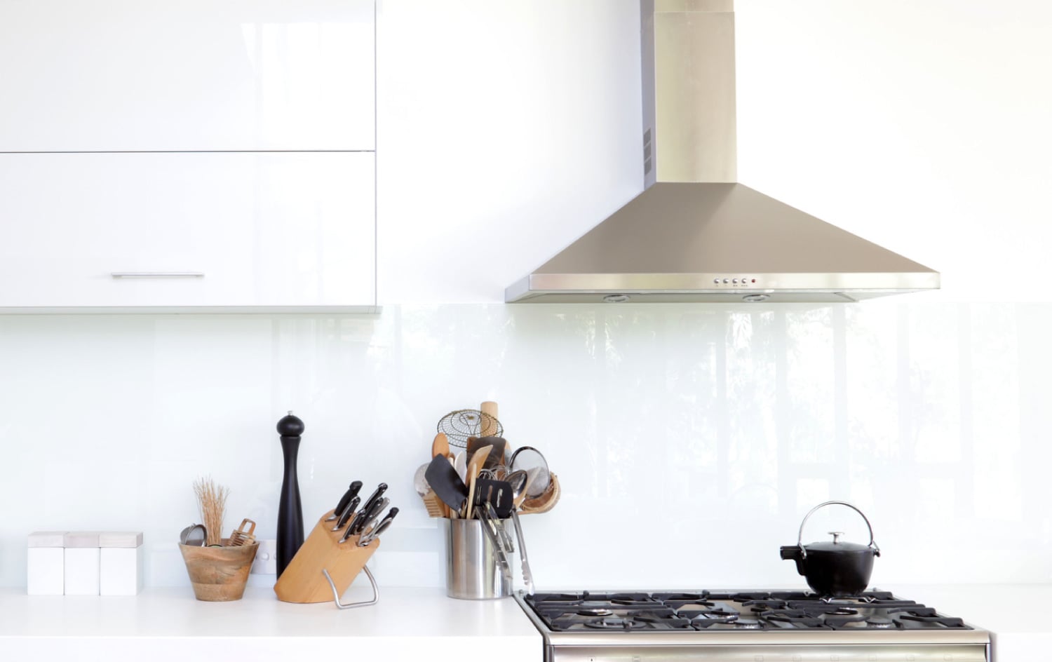 Metal extractor canopy above a white kitchen cooking area