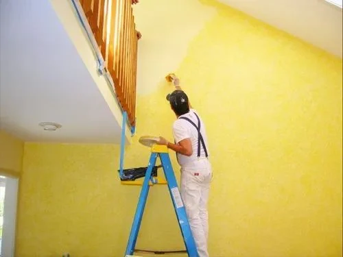 A painter working near a room ceiling